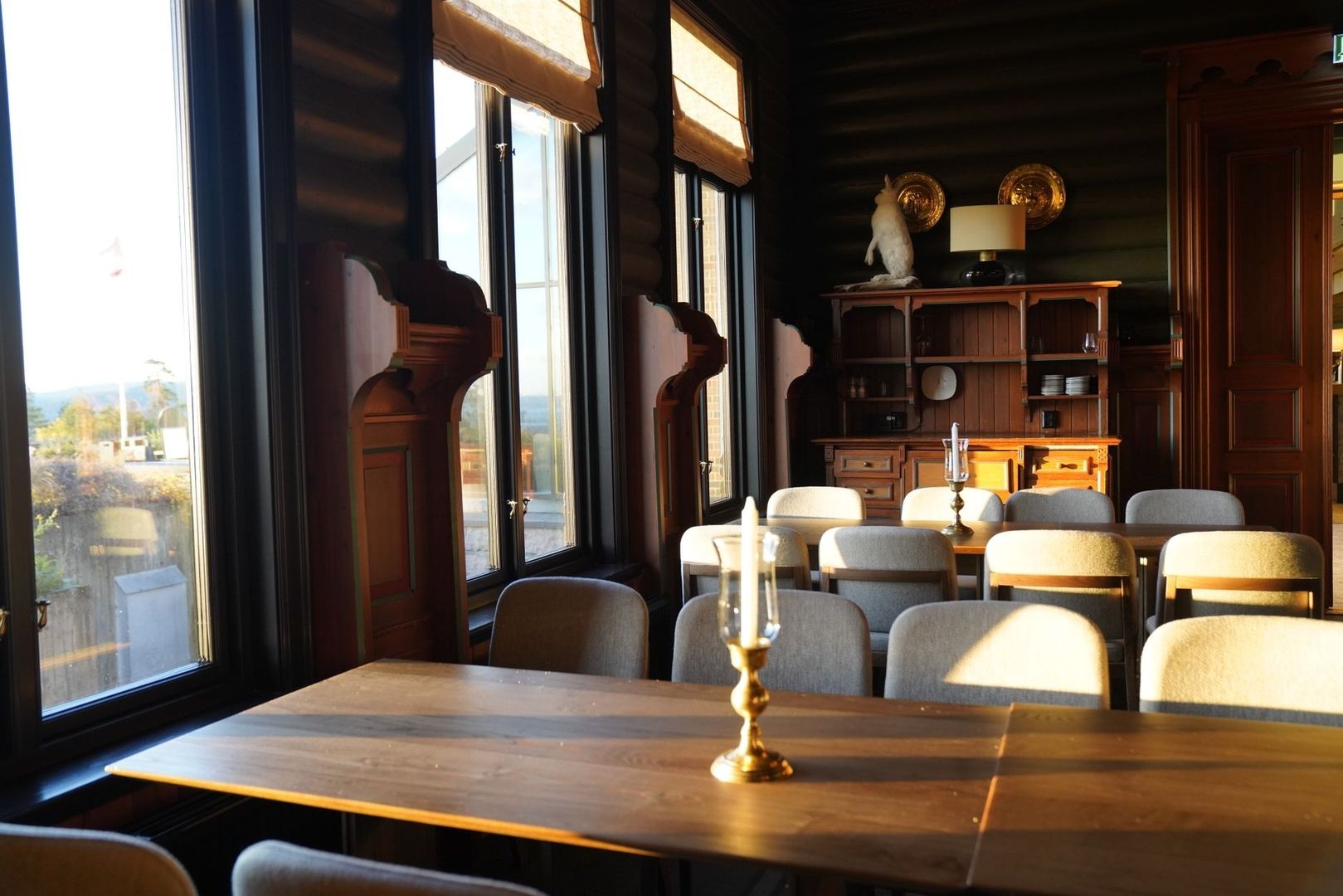 Elegant wood-paneled dining room with tables, chairs, and candleholders