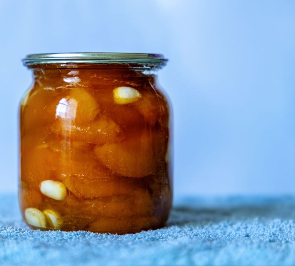 Glass jar of orange fermented vegetables with garlic cloves