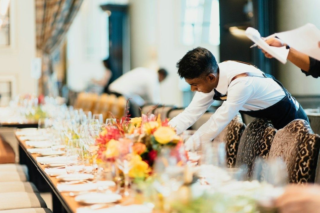 Restaurant servers carefully prepare an elegant, flower-filled dining table