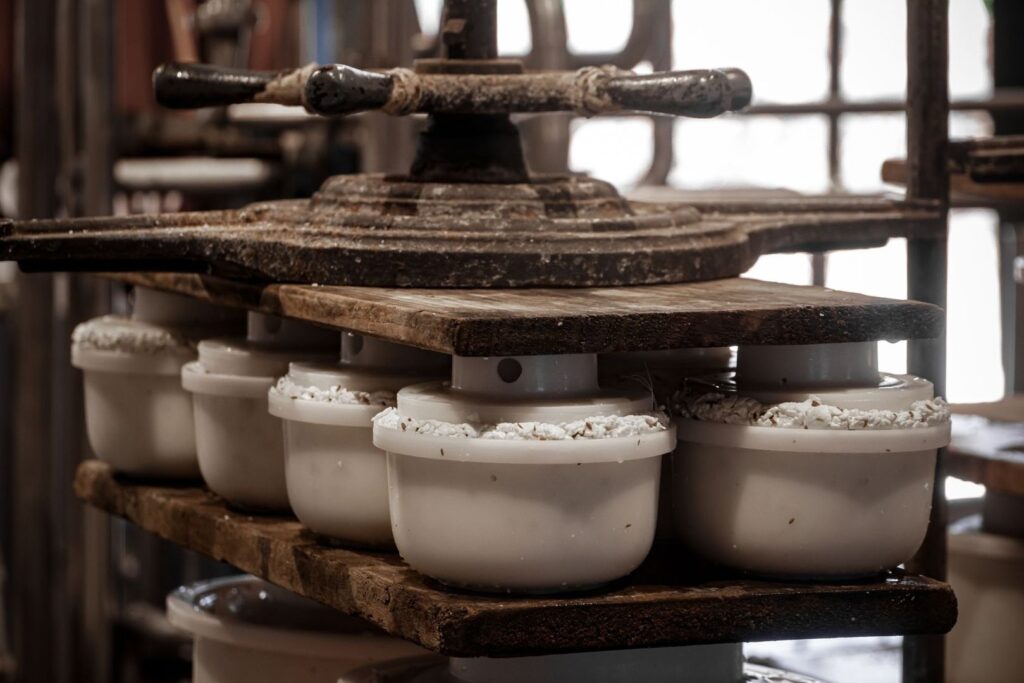 Traditional wooden press holding several white fermentation crocks